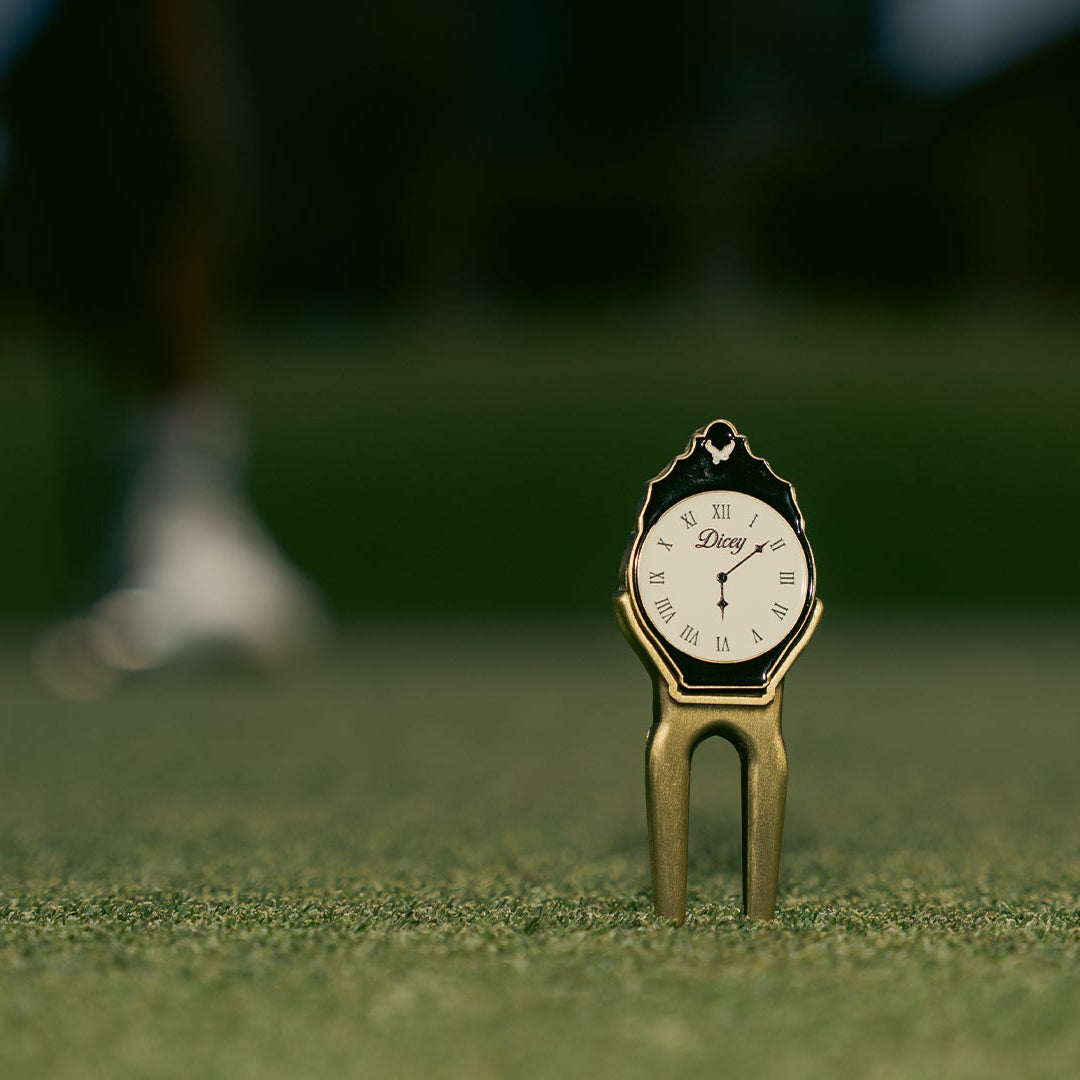 Golf divot tool with clock face on a green golf course